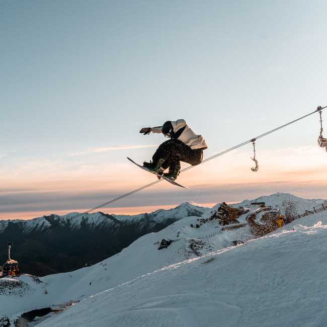 Snowboarder doing a trick at Coronet Peak at Sunset
