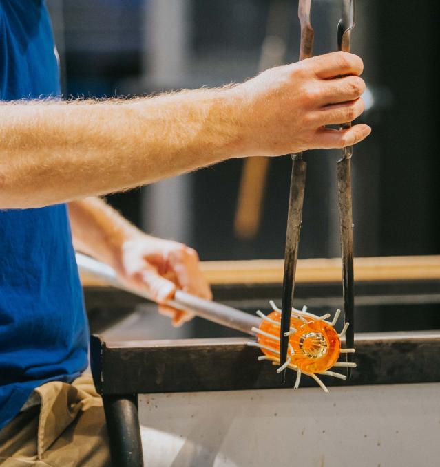 A man works hot glass during a glassblowing demonstration at the Flint Institute of Arts.