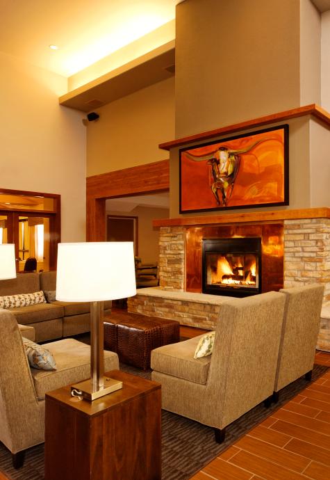 The lobby of the Holiday Inn Express with a cozy seating and dining area surrounding a fireplace.