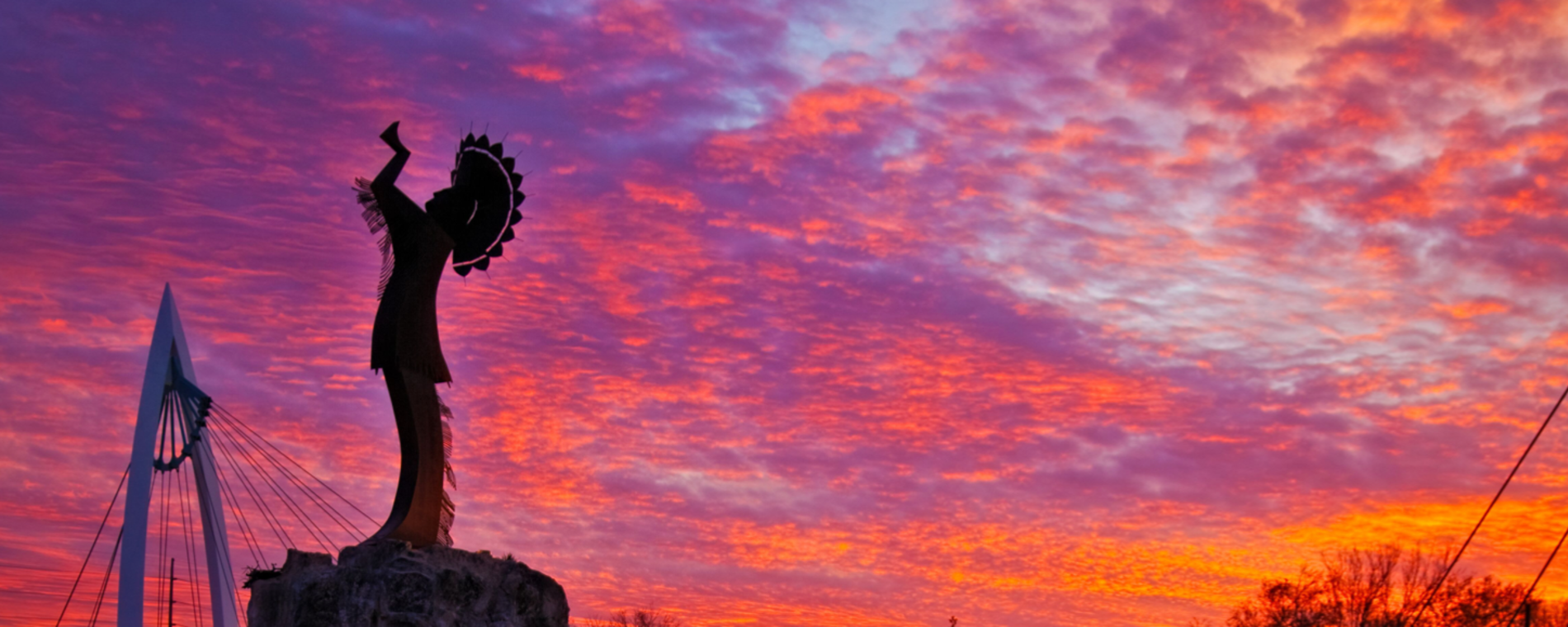 The Keeper of the Plains stands under a beautiful purple and orange sunset in Wichita