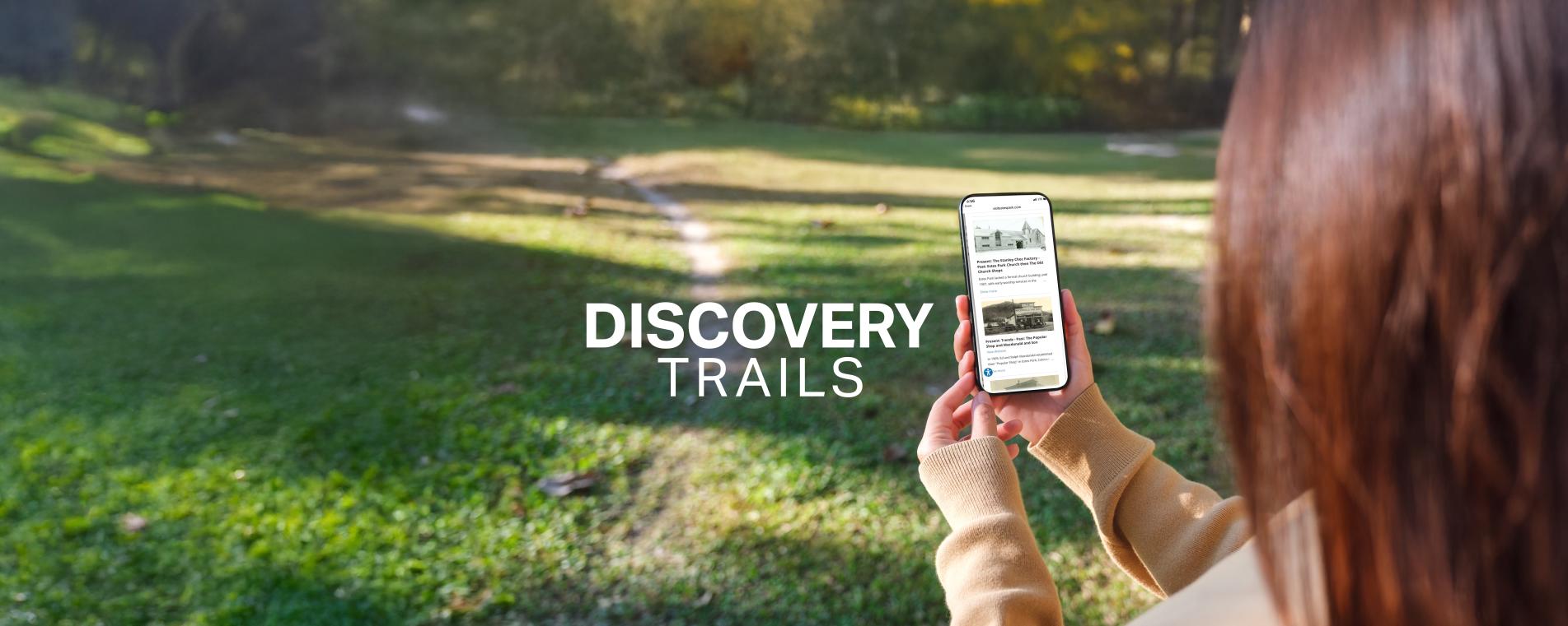 Woman holding a phone. Text reading "Discovery Trails".