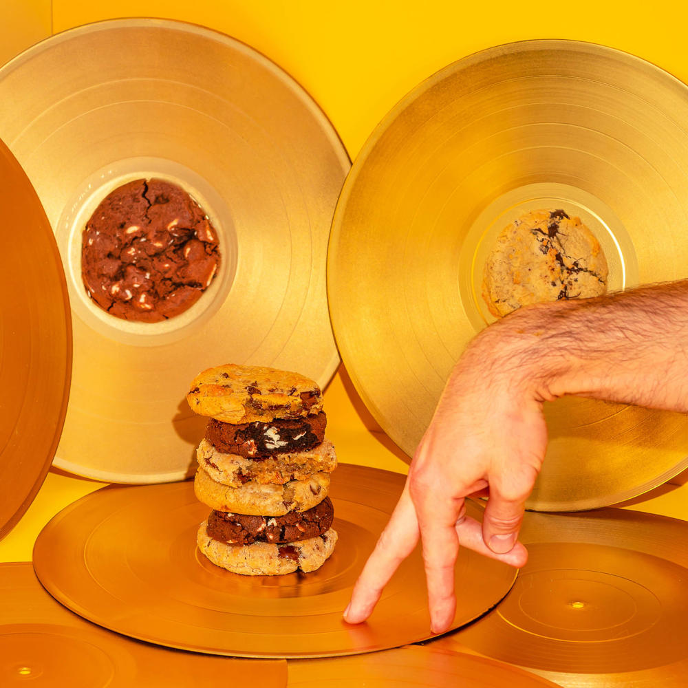 Golden records topped with stacks of cookies, along with a hand positioned to look like a walking person.