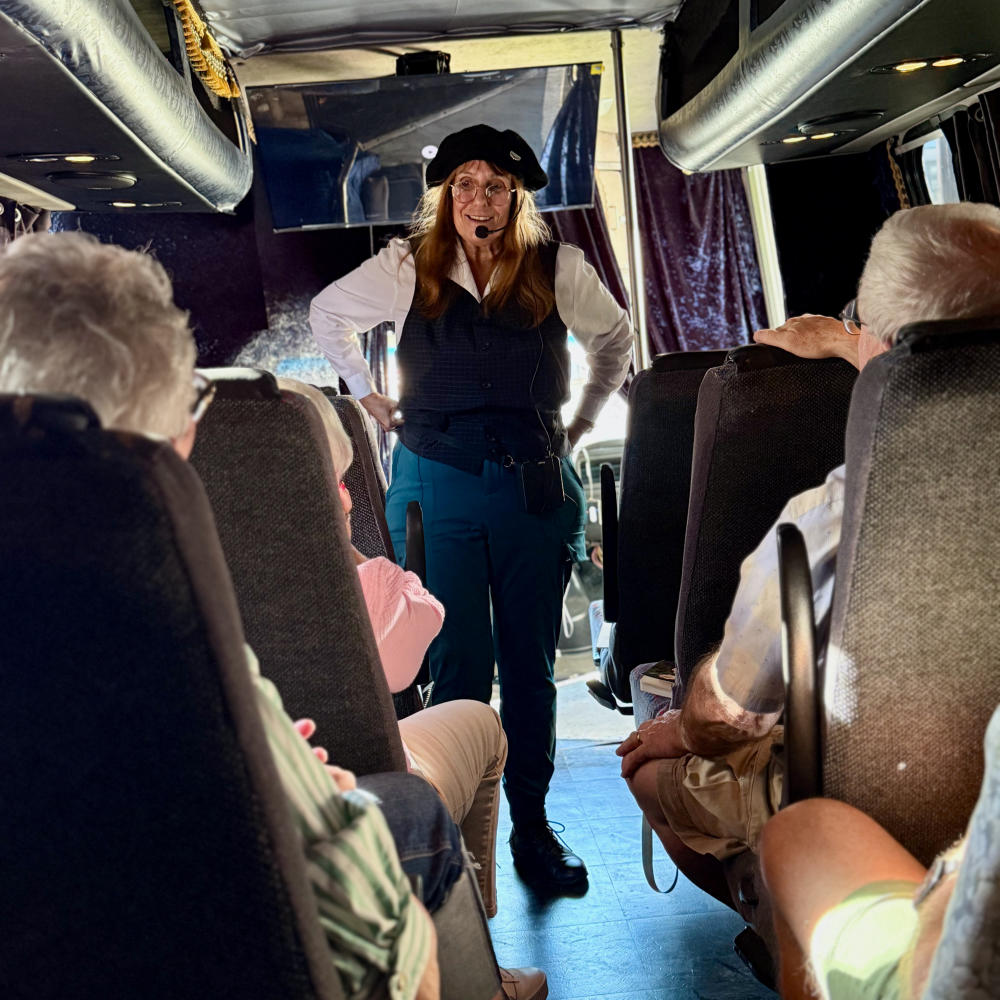 Tour guide smiling to a group of tourists on the Dam Good Tour tour bus.