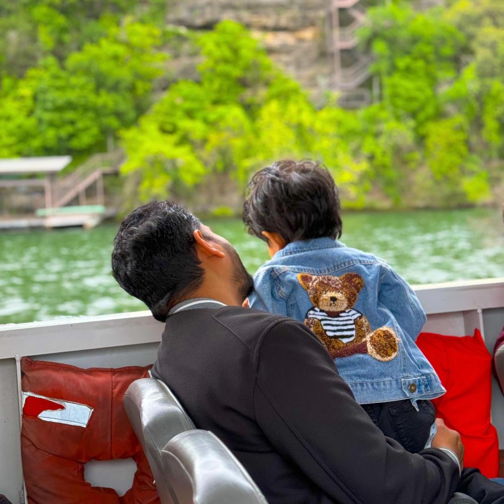 Dad and sun looking over the side of an Austin Duck Tour boat on Lady Bird Lake.