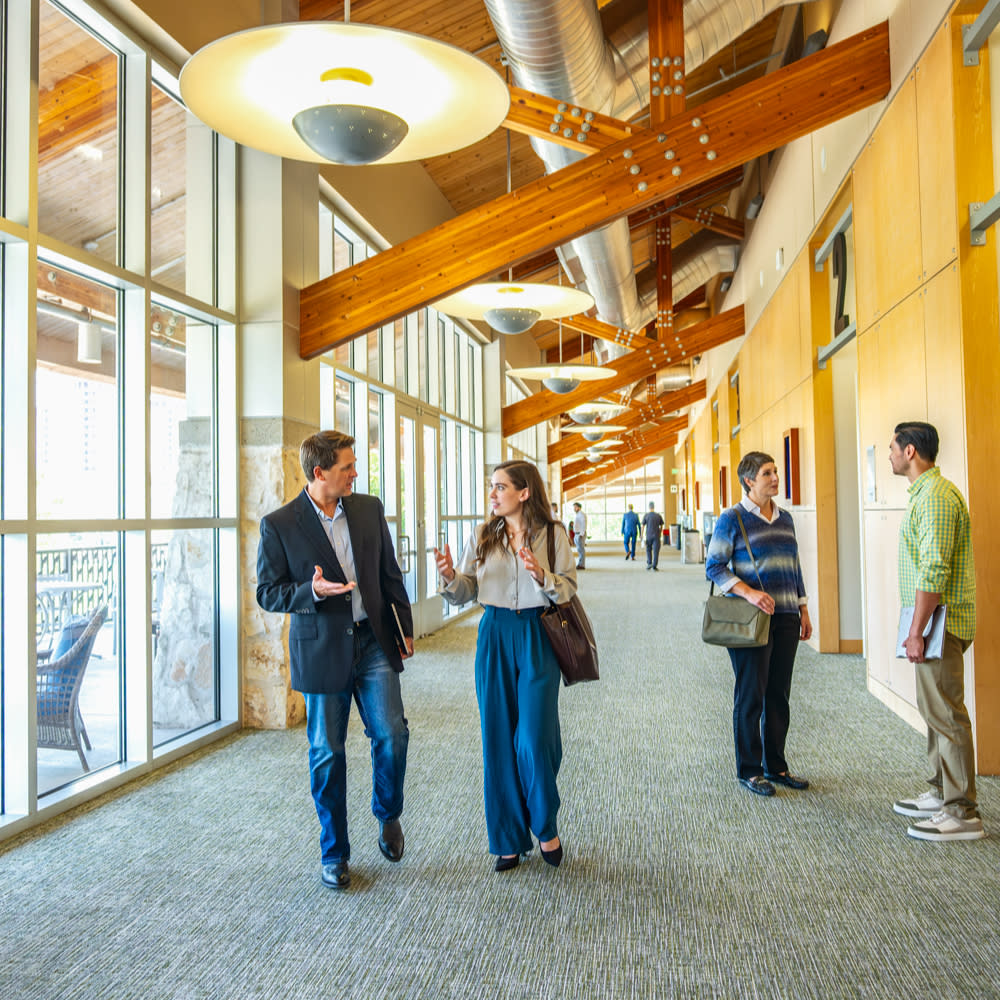 Men and women in professional attire gathering in pre-function space during a conference.
