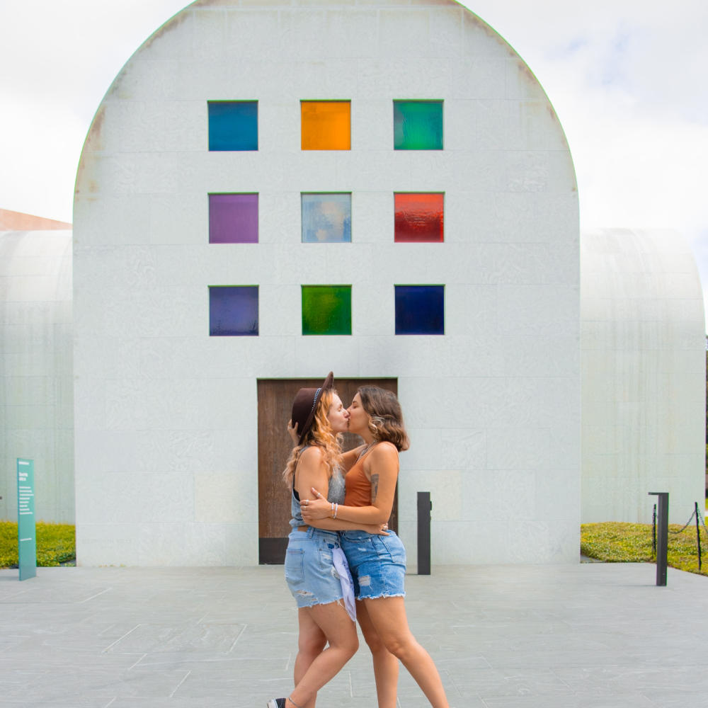 Two women kissing in front of "Austin" at the Blanton Museum of Art.
