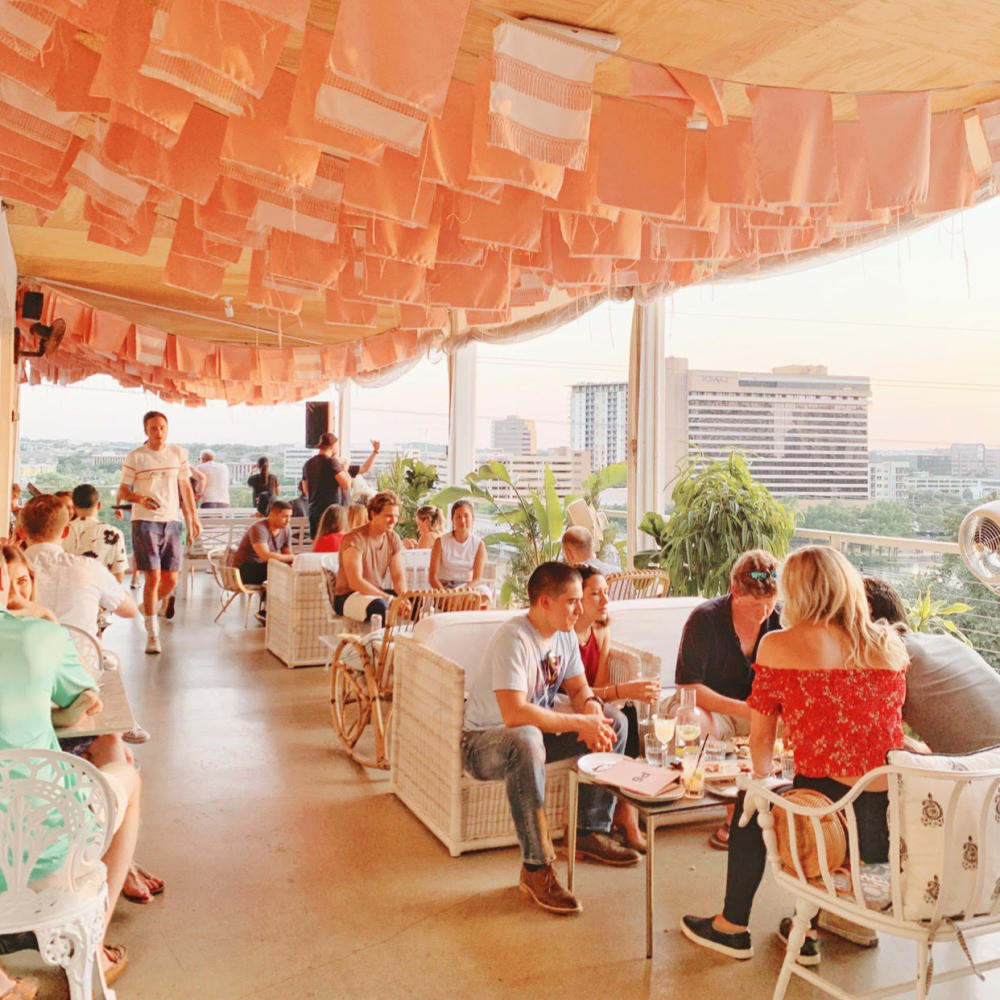 People sitting at mixed chairs and couches on the P6 rooftop at the LINE Hotel Austin.