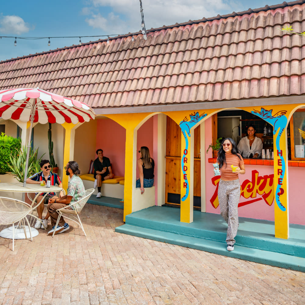 People sitting around an outdoor courtyard with a colorful bar.
