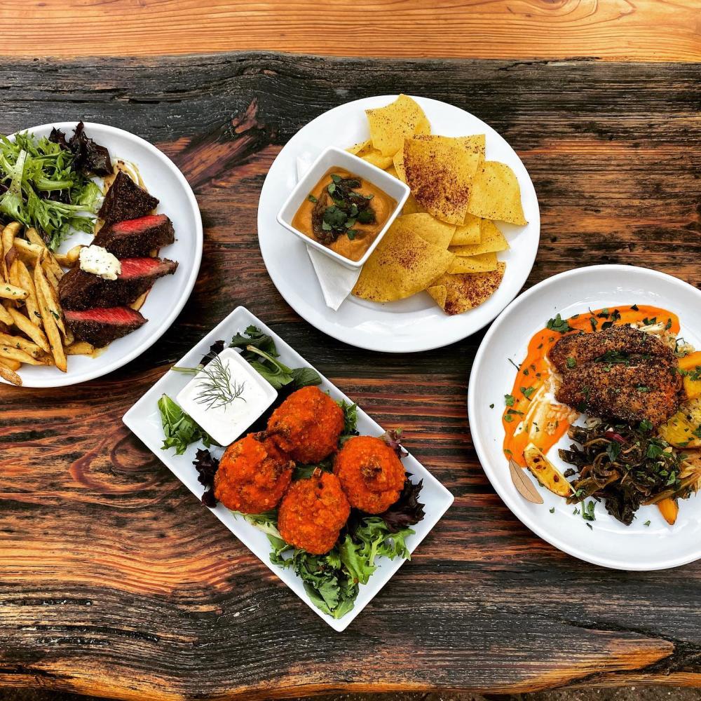 Dinner plates with various types of food on a wooden table.