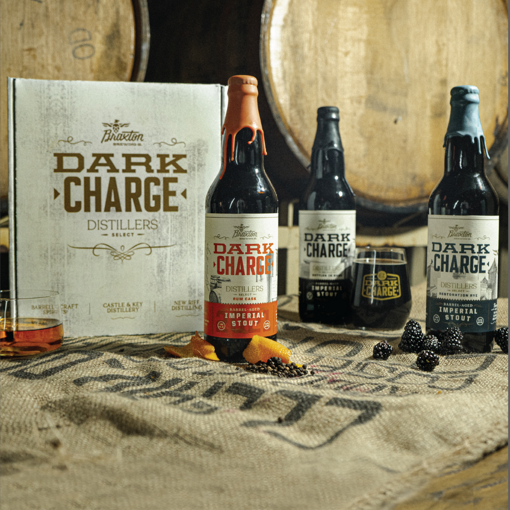 A box reading Dark Charge Distillers with three bottles of Braxton's Dark Charge Imperial Stout