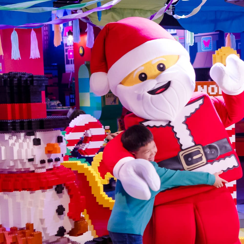 Young boy hugging life-size lego Santa character