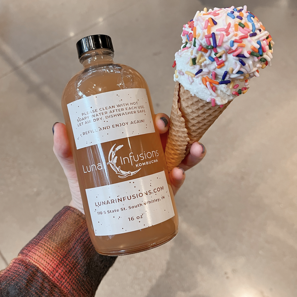 Bottle of Kombucha and an ice cream cone in one hand