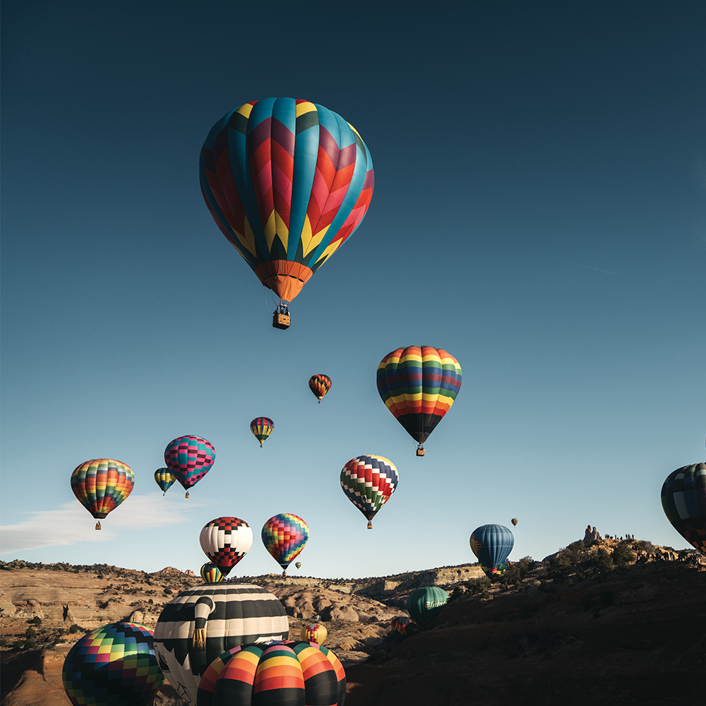 colorful hot air balloons against a blue sky and red rock formations