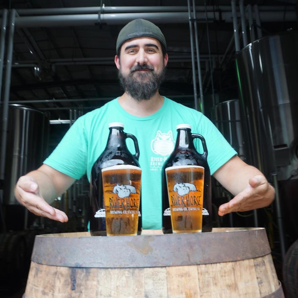 A man at river horse brewing with two beers and two growlers