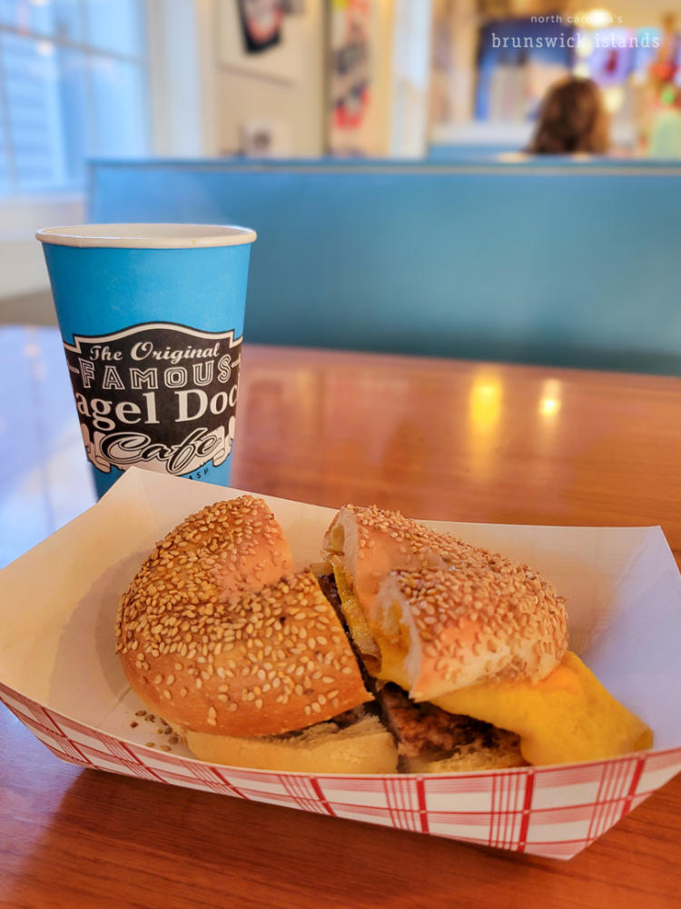A sesame bagel with sausage egg and cheese and a coffee on the side