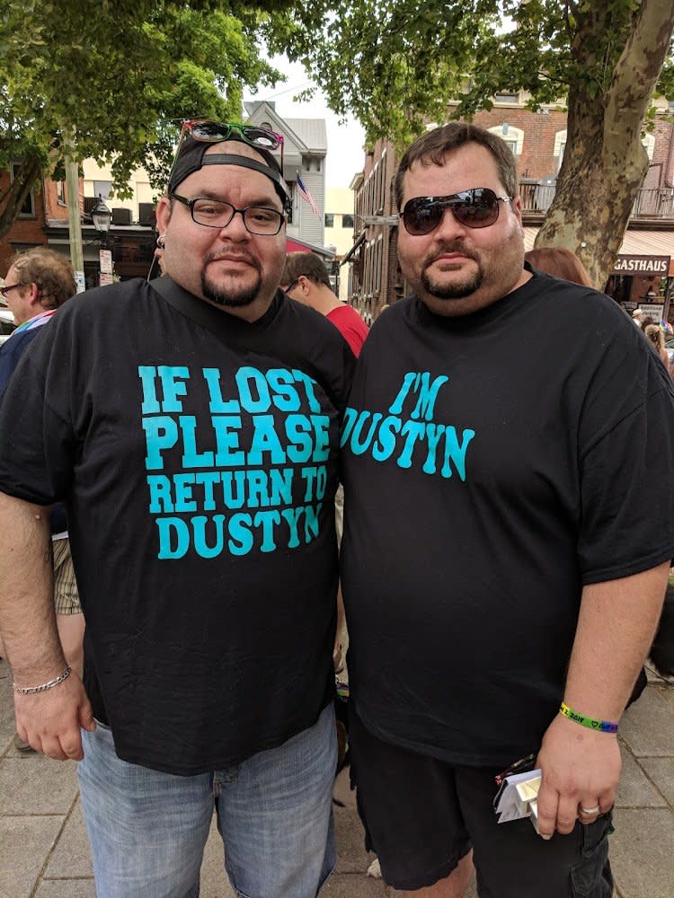 Two men in black shirts. The one on the left says If lost please return to Dustyn in blue letter. The shirt on the right says I'm Dustyn in blue letters.