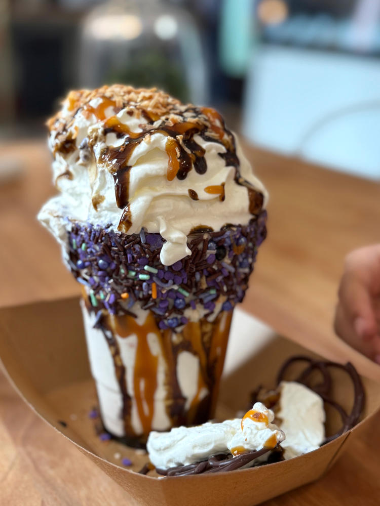A monster milkshake features a blend of cookies, ice cream, syrups, and a pile of housemade whipped cream from Cherri's Chocol'Art.