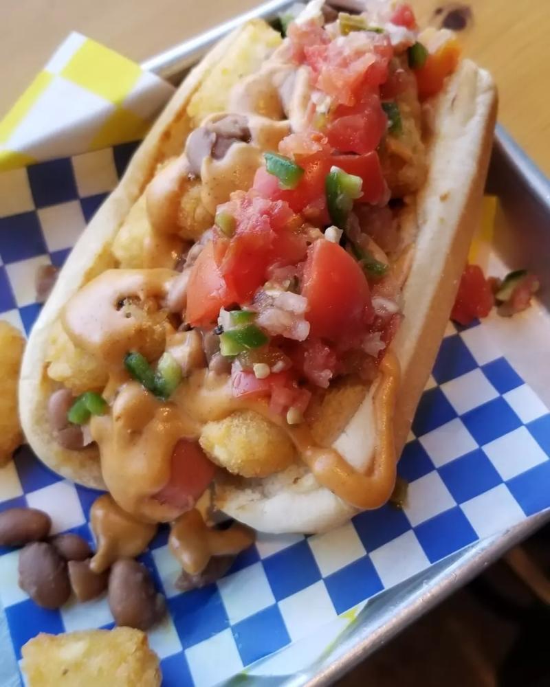 A hot dog with Tater Tots, Pinto Beans, Nacho Cheese, Flame Roasted Jalapeňo Salsa from Clowndog Hot Dog Parlor
