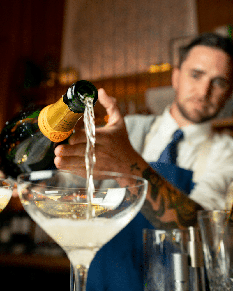 Man pouring champagne at bar-cecil drinks