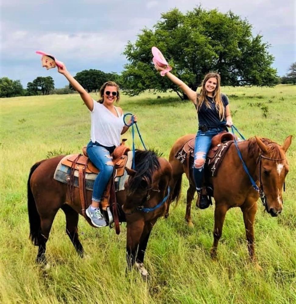 Horseback riders wave their cowboy hats at Tres Molinas Ranch & Resort in Fredericksburg, TX