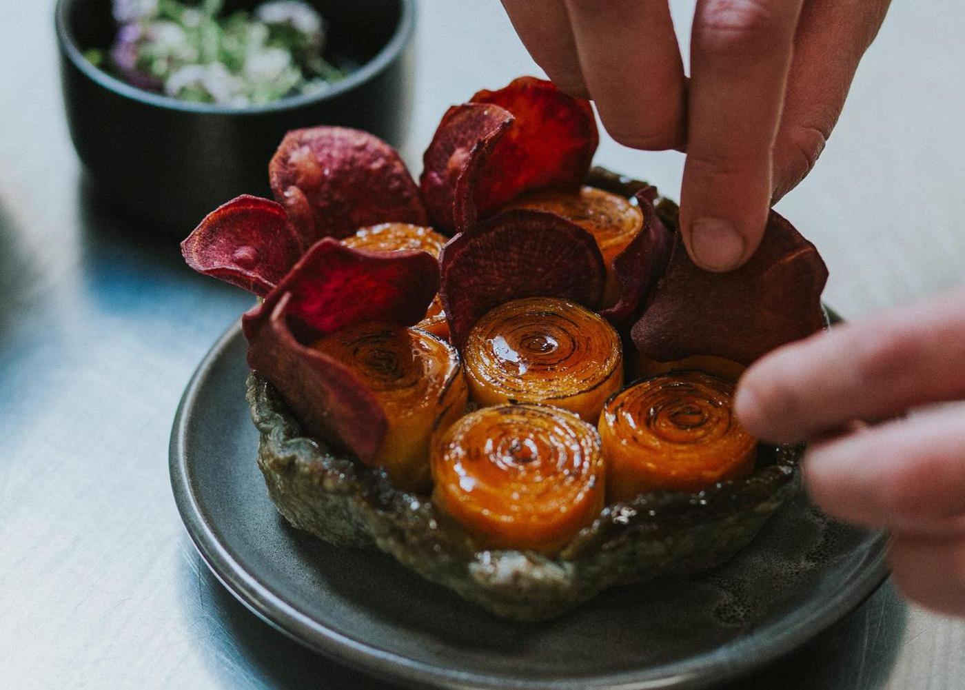 Close up of a colourful Kumara Tarte Tatin dish being prepared by a chef