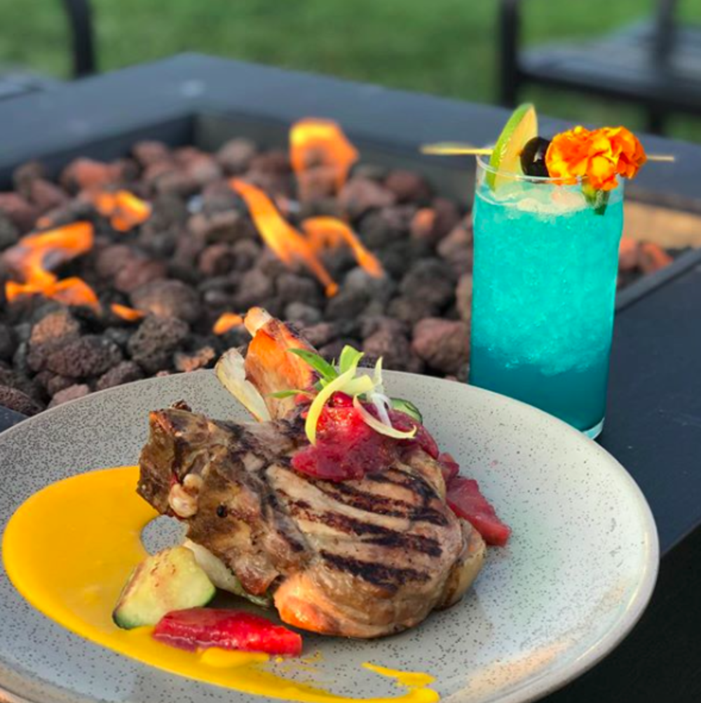 Meal by a fire pit with a blue cocktail at Brick Farm Tavern in Mercer County