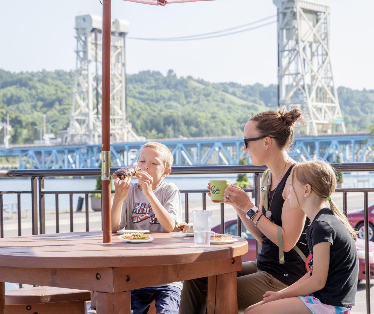 Family of three sitting on Roy's patio eating donuts.