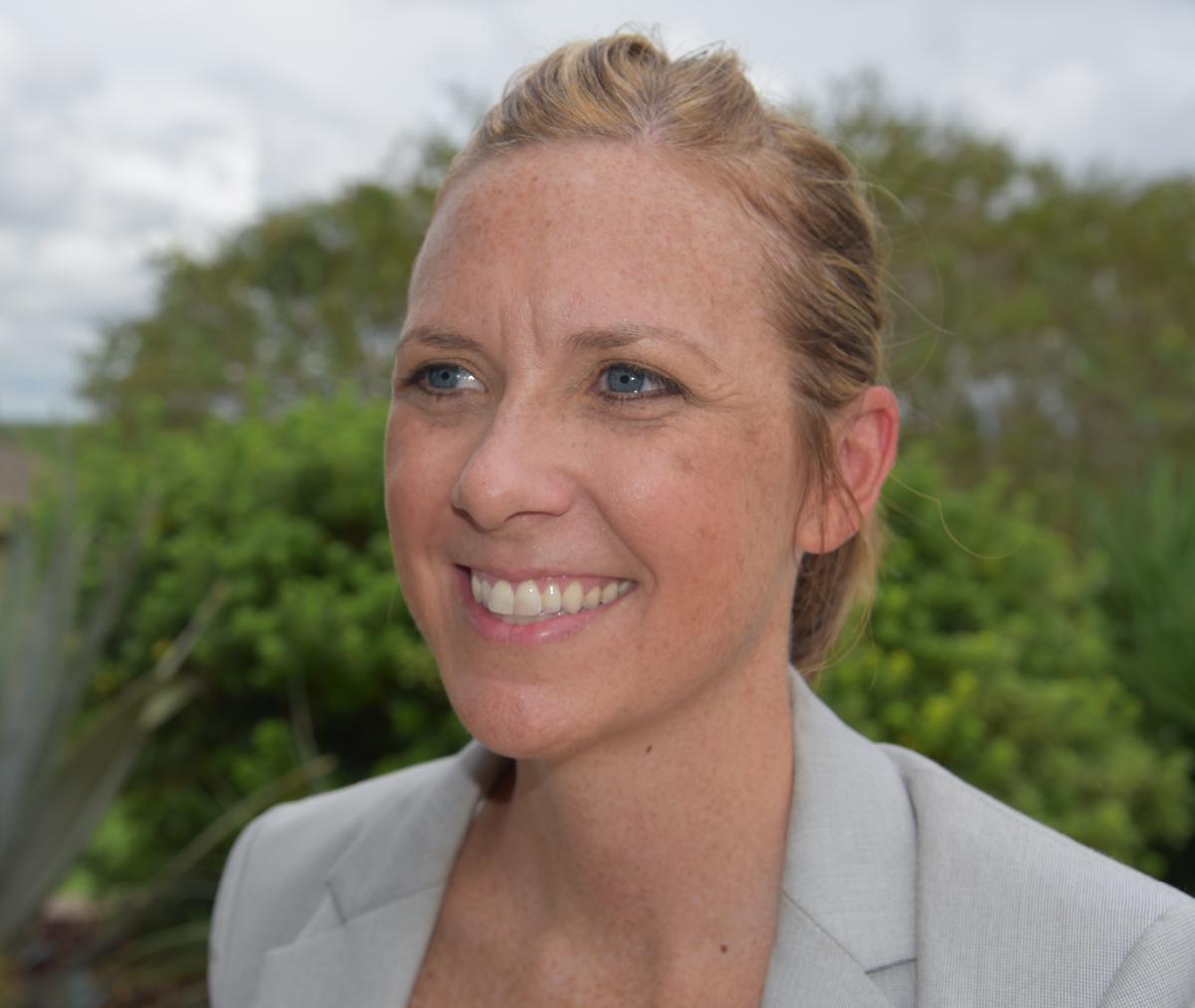 Dr. Kiersten Stanzel smiles to the side of the camera in front of a green, outdoors background.