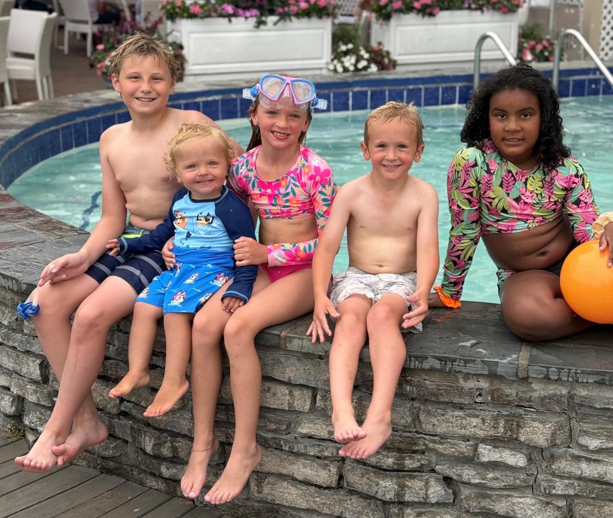 A group of Mackinac Island kids sit on the side of the hot tub at The Pink Pony