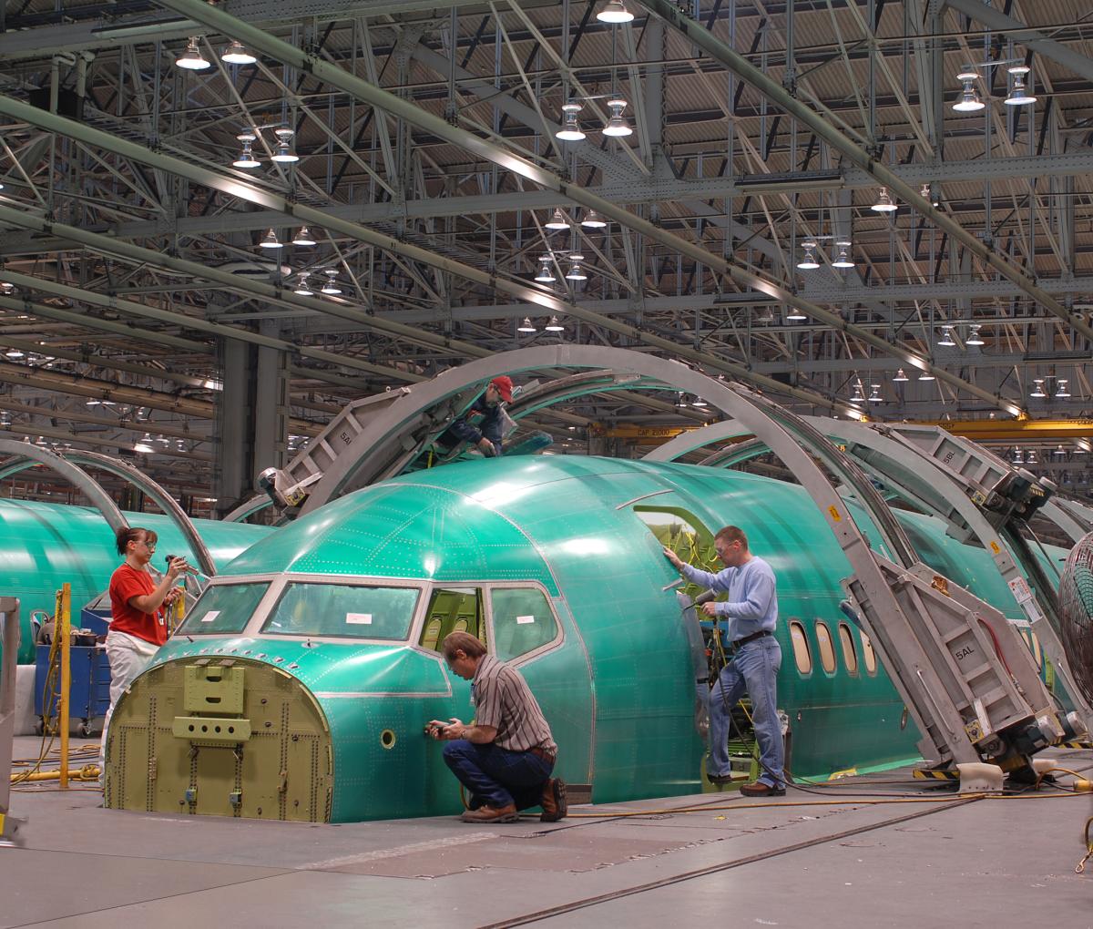 Spirit AeroSystems workers work on a fuselage inside a building