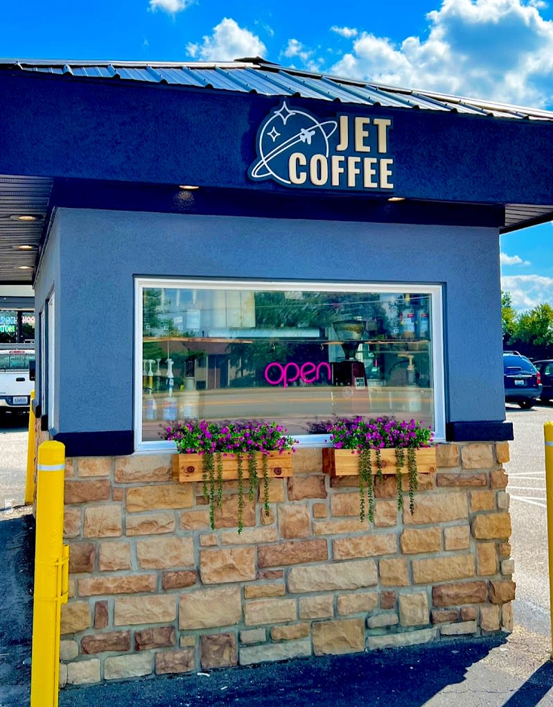 Image of the Jet Coffee drive through which is a small blue building with a window and flowers.