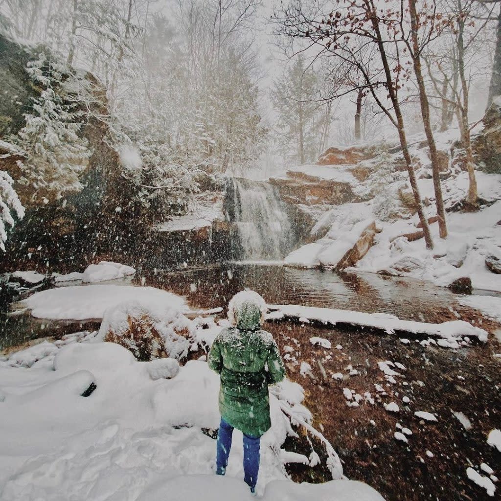 Woman standing in front of frozen waterfall.