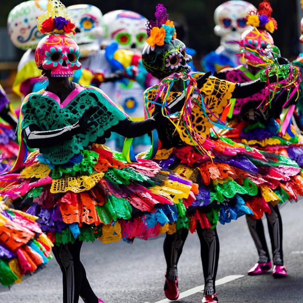 Dancers dressed in bright colors and skull decorations celebrate Day of the Dead