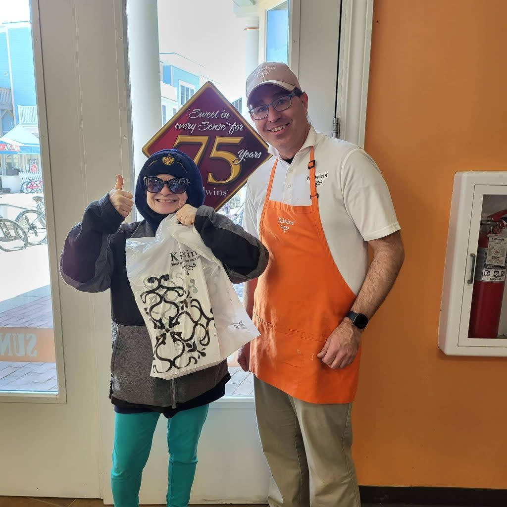 The first customer of the season at Kilwins Mackinac Island gives a thumbs-up to the camera while holding a bag of fudge.