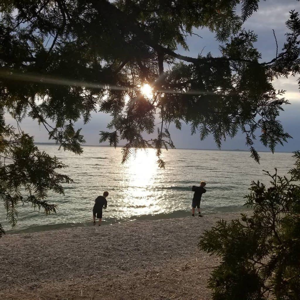Two Boys Standing on Shore and Skipping Stones in Water Surrounding Mackinac Island