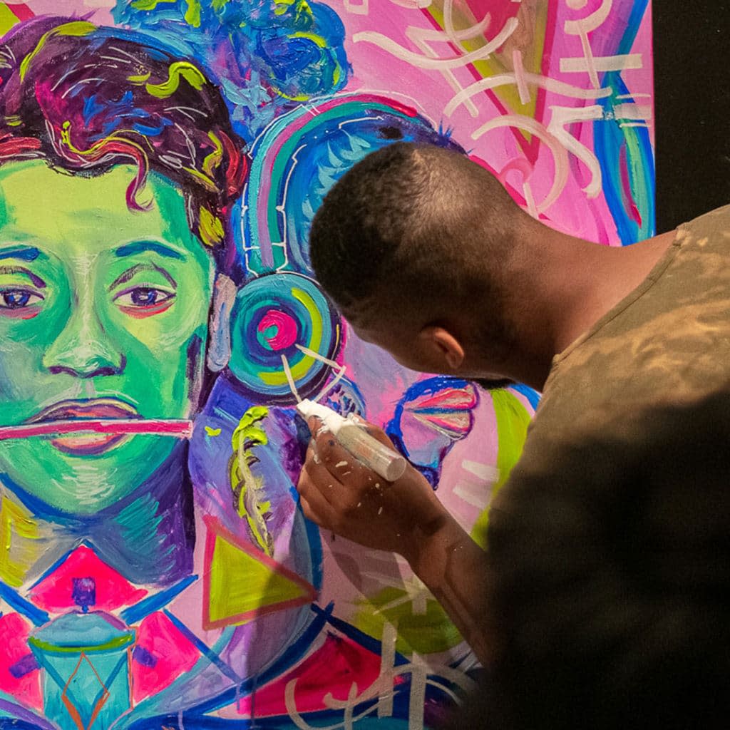 Person painting on large, colorful canvas