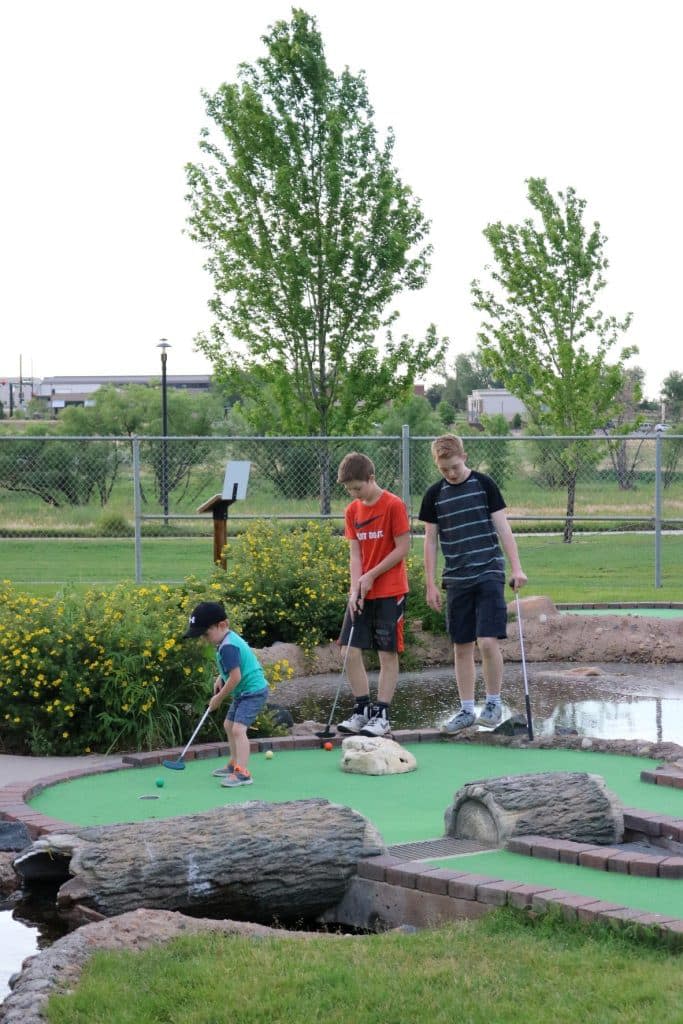 Image of three white children putting on the green at the Family FunPlex miniature golf course in Greeley, Colorado