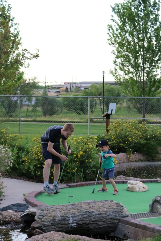 Image of two white children celebrating the smaller child's hole-in-one at the Family FunPlex miniature golf course in Greeley, Colorado