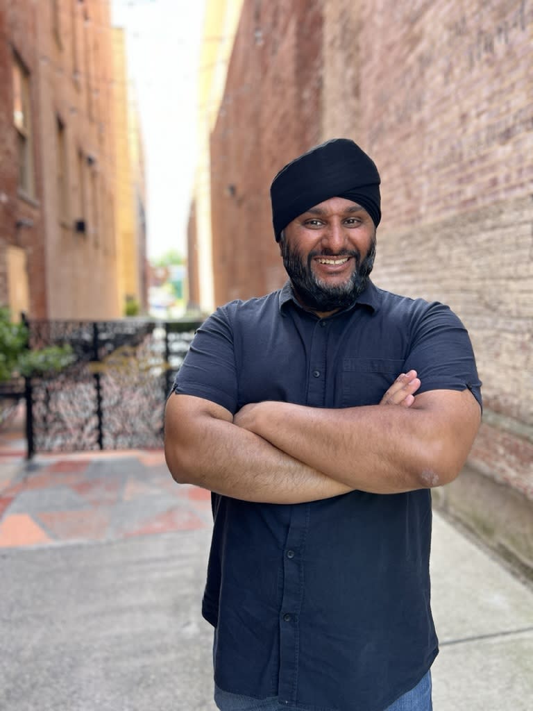 Bally Bansal, owner of Aman's Artisan Indian Cuisine, smiling in an alleyway in Easton, PA