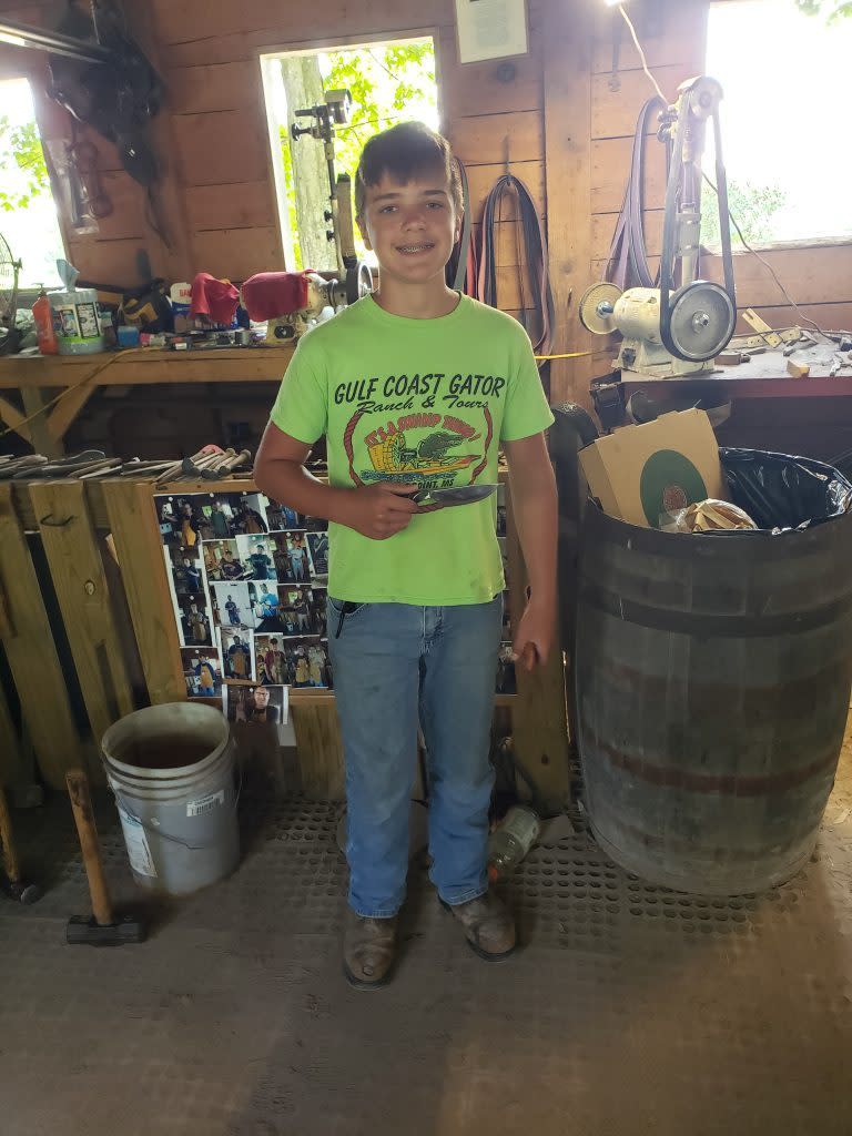 A teenage boy shows off his handmade souvenir knife at Forge A Memory Blacksmith Shop on Mackinac Island