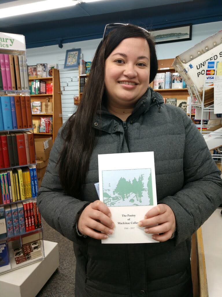 The first customer of the season at The Island Bookstore on Mackinac Island holds a poetry book that she bought.