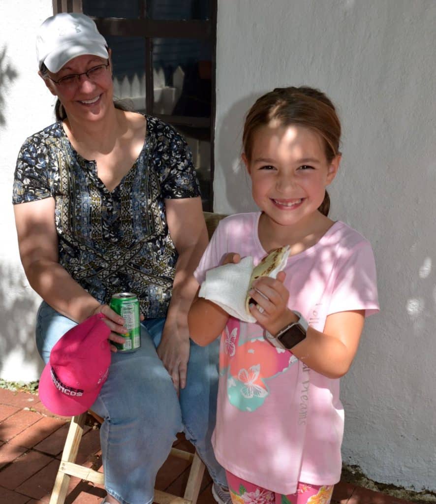 A little girl with a pink shirt and a pony tail takes a bite from a freshly made tortilla at the Centennial Village Museum during Potato Day