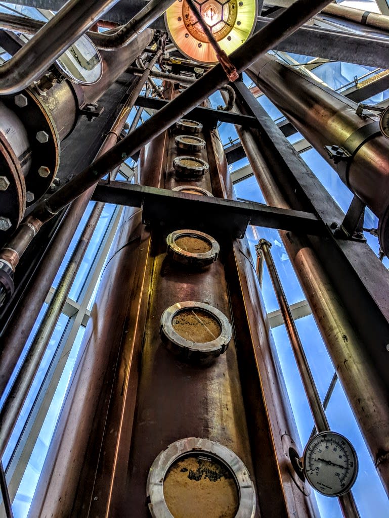 A copper column with metal circles on it with the blue sky in the background