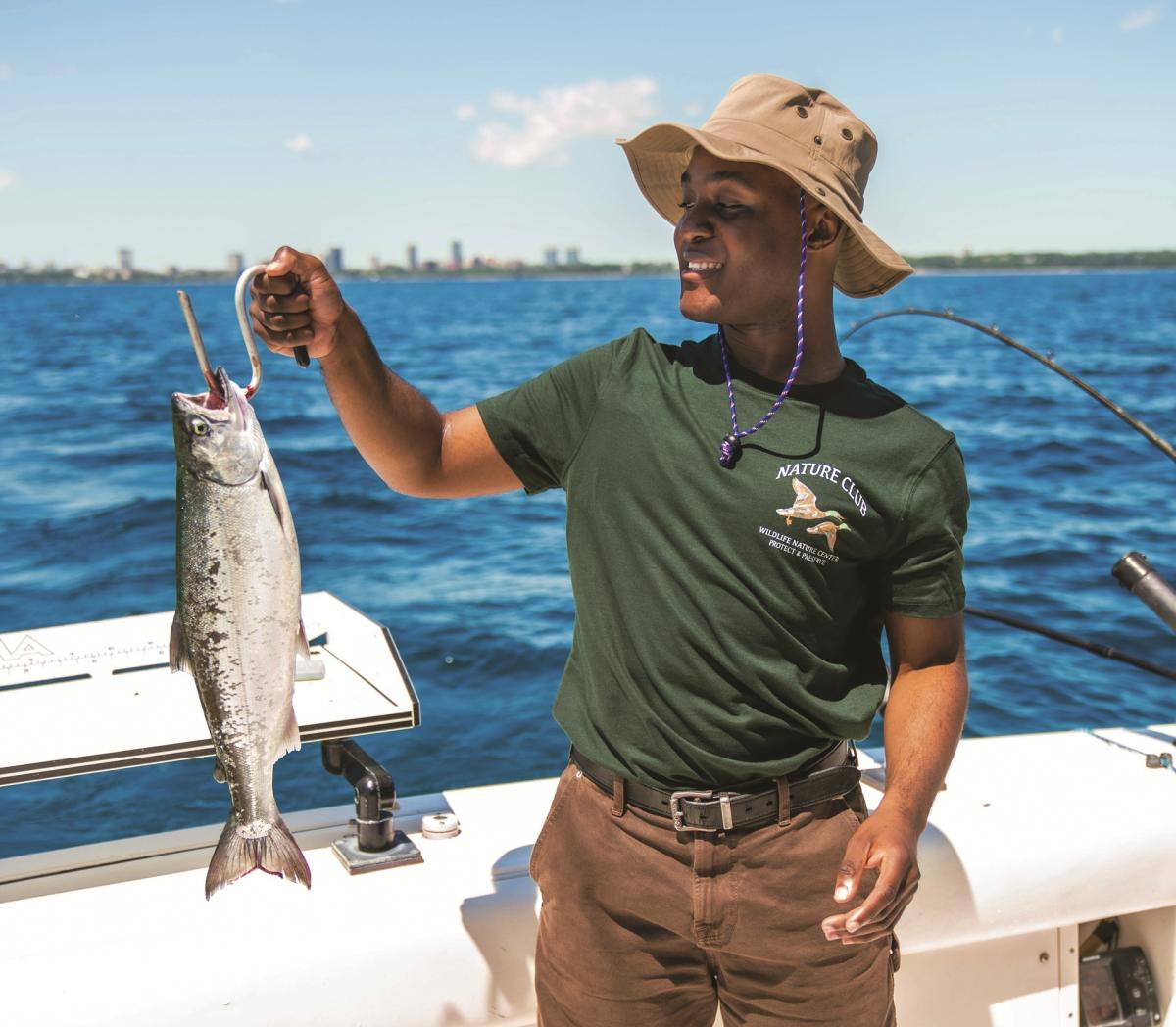 A man holds up a freshly caught fish aboard a charter boat on Lake Michigan.