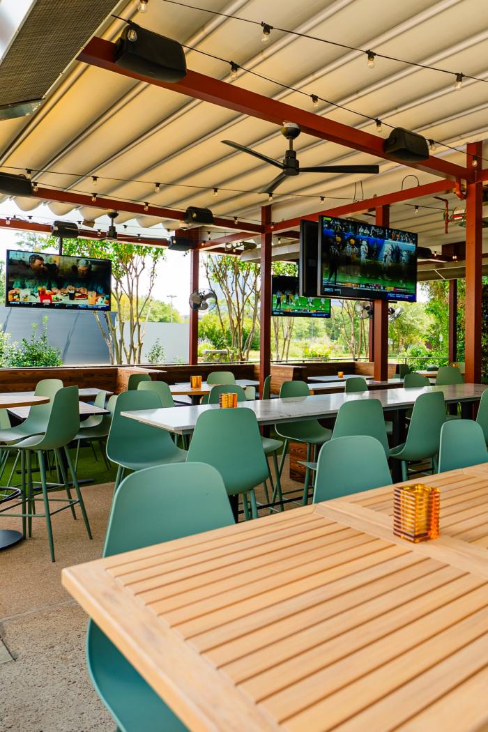 The patio at LOCAL Public Eatery is spacious, featuring at least a dozen 2-4 person tables and 3 tables seating 8 or more. The metal awning is retractable. The metal beams prop up at least 5 flat screen TVs.