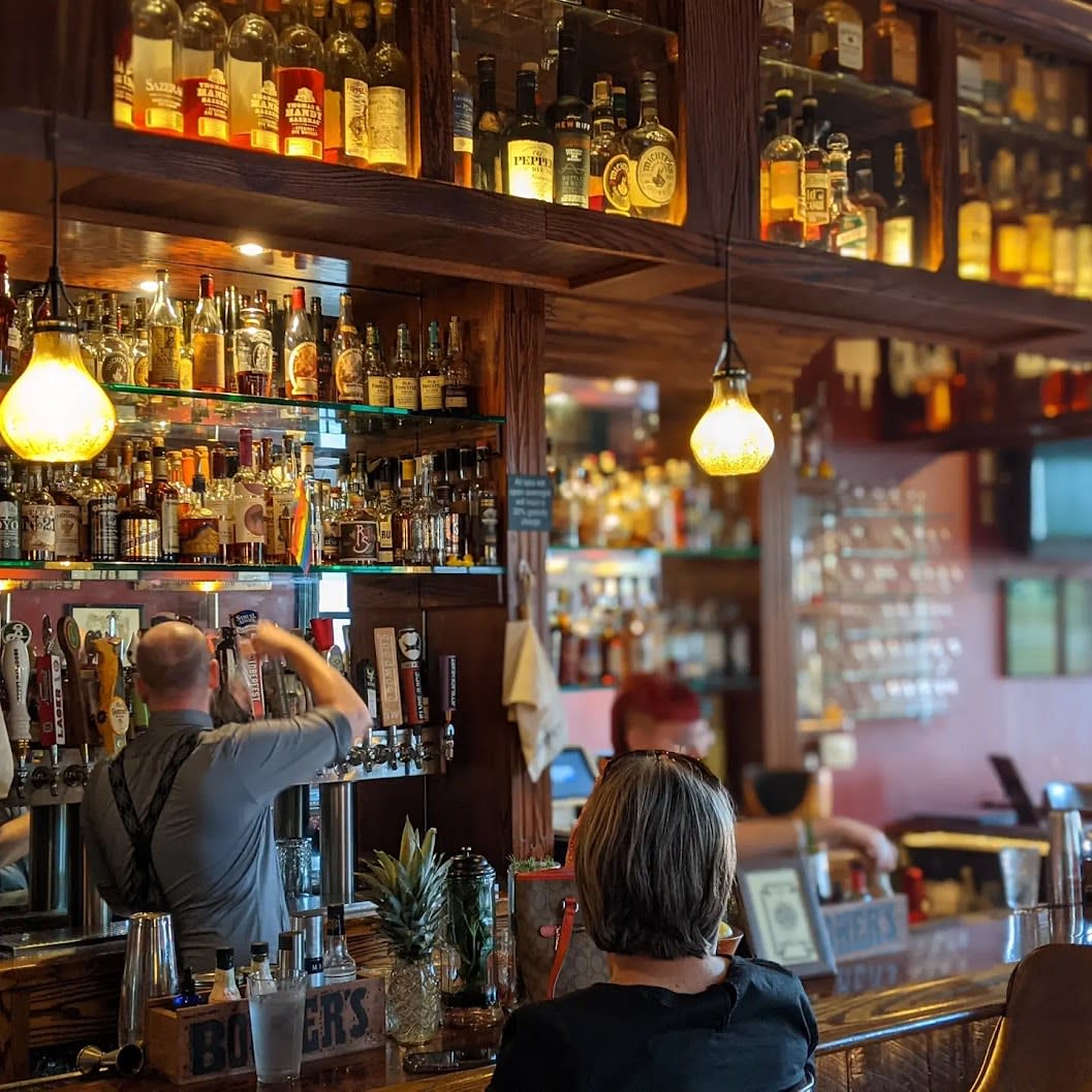 Woman seated at the wooden, well-stocked bar at Wiseguy Lounge in Mainstrasse Village