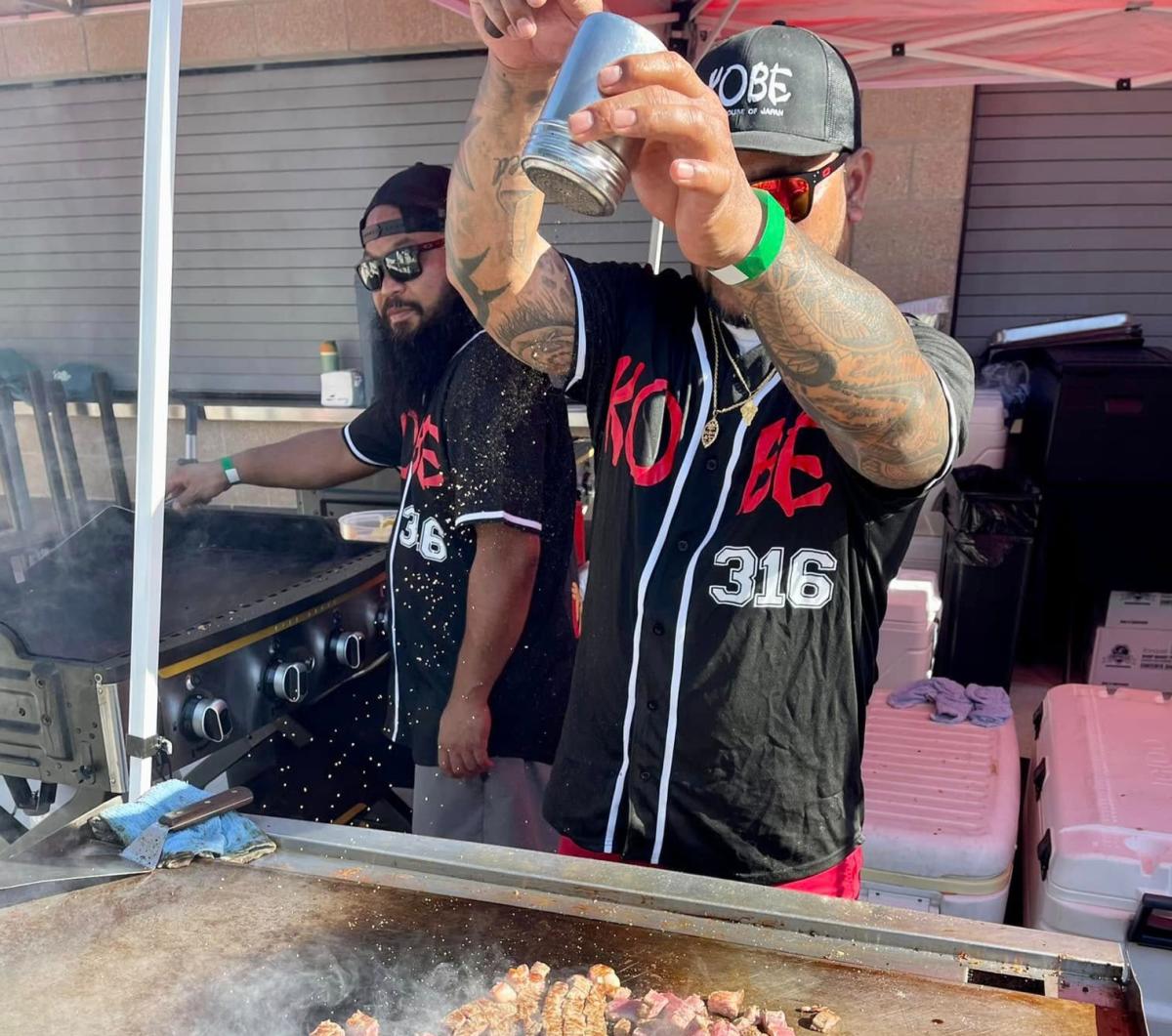 A man cooks meat over a flat top grill during Asian Night Market