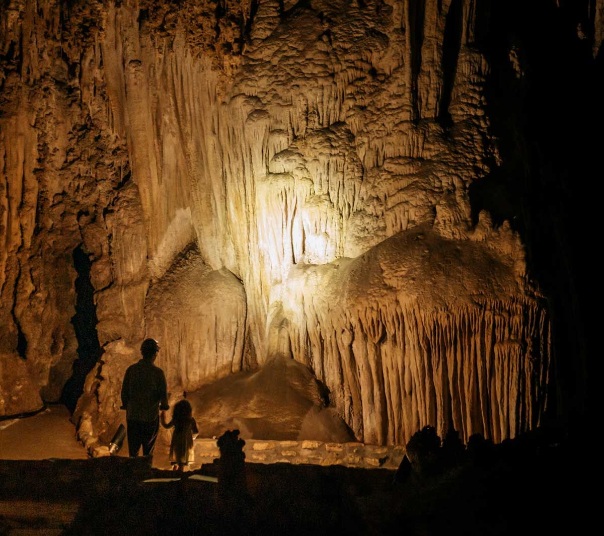 A man and child observe flow stone formations in Carlsbad Caverns