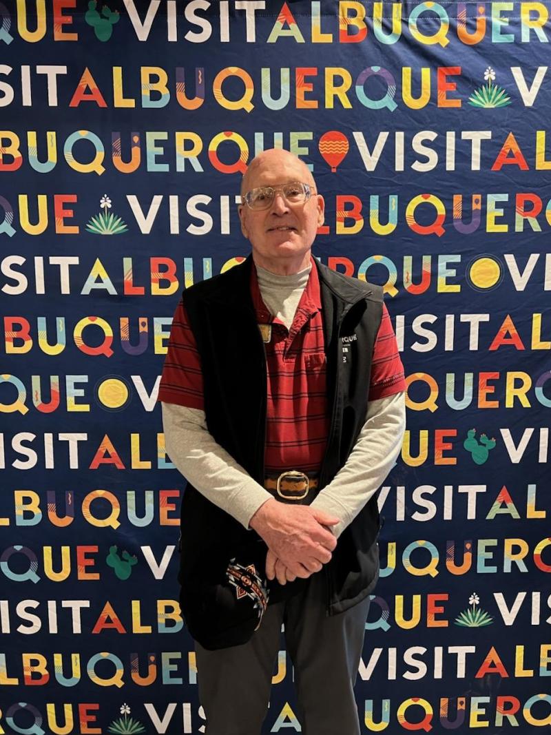 A picture of Visit Albuquerque volunteer Dave Fontaine in front of a Visit Albuquerque backdrop.