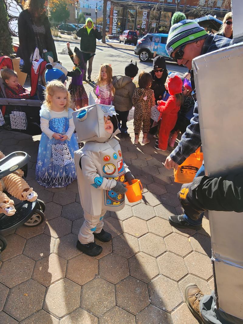 Kid dressed as robot trick or treating in a group of kids also dressed up